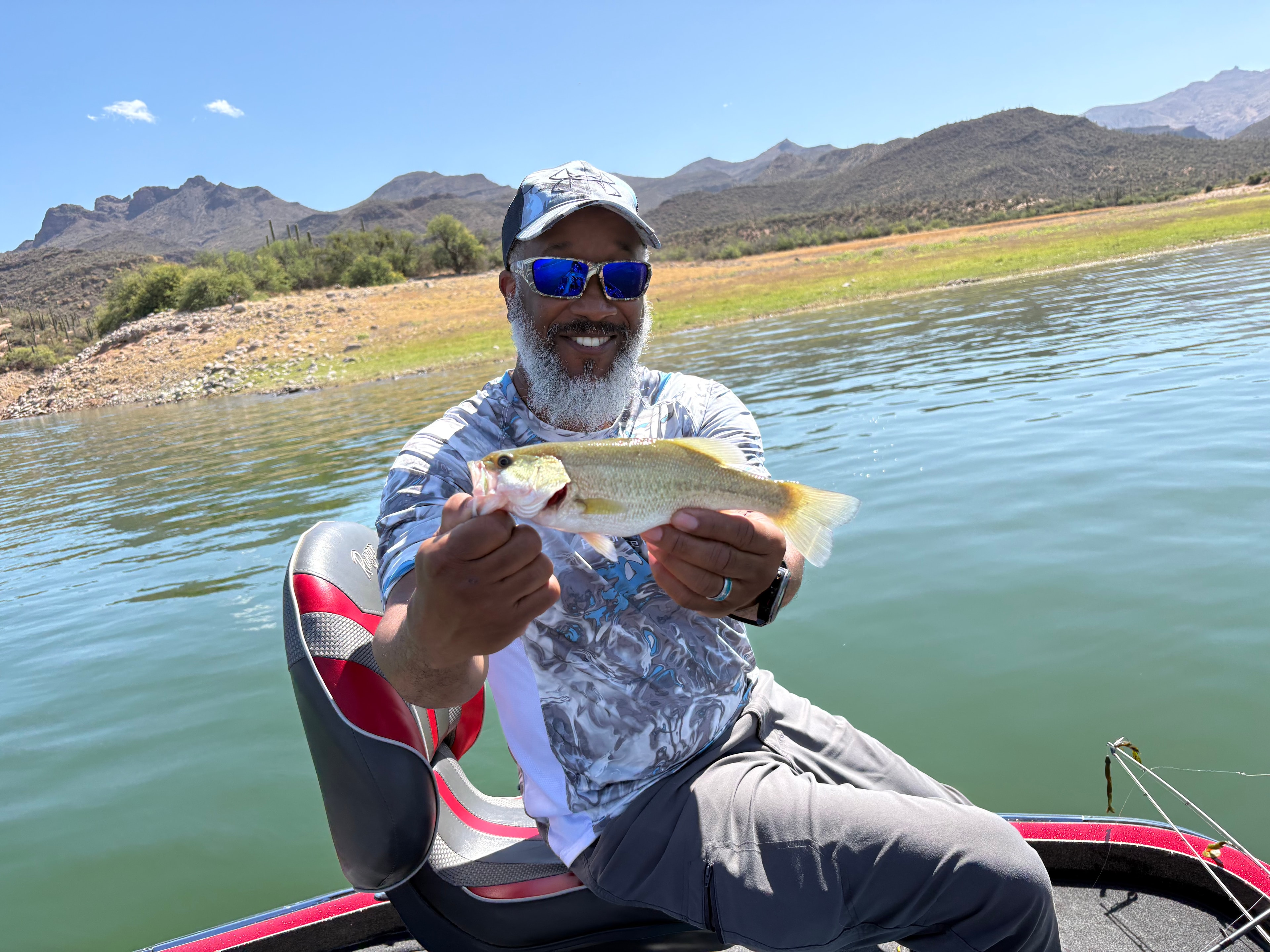 Man holding caught fish with lake and mountains